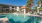 a swimming pool with chairs and umbrellas next to a house
