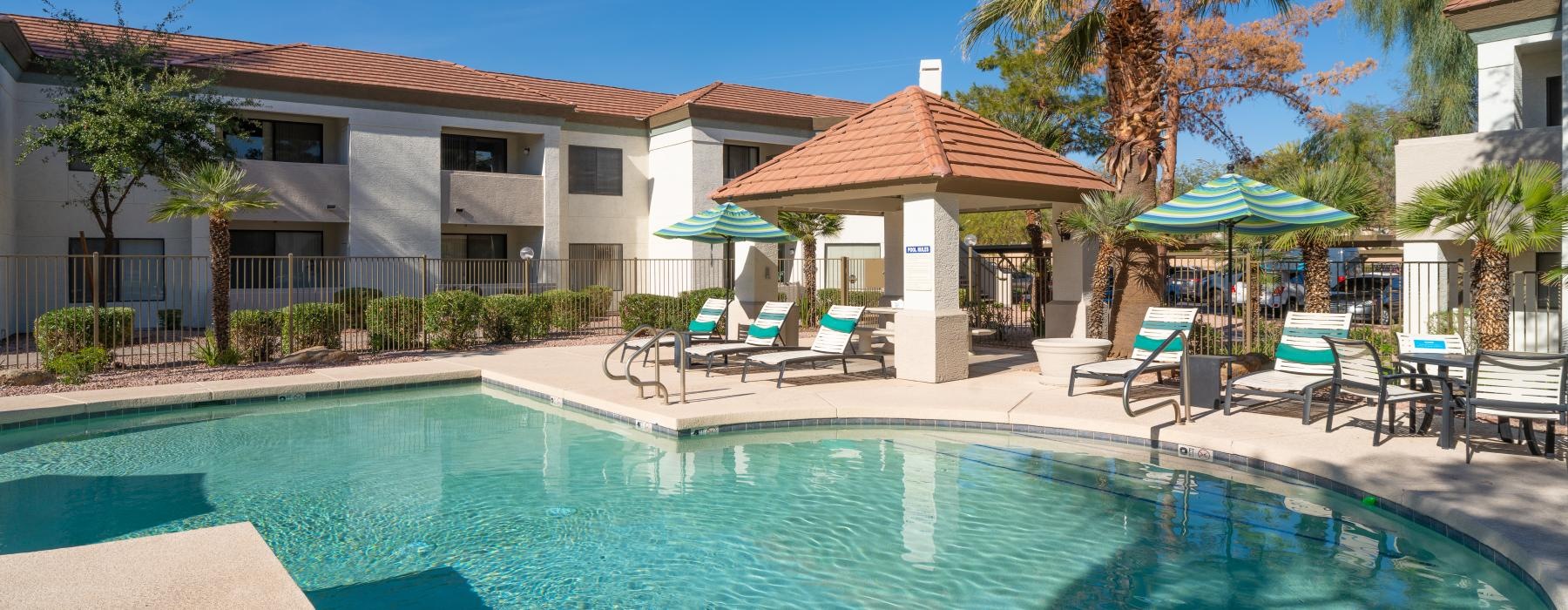 a swimming pool with chairs and umbrellas next to a house